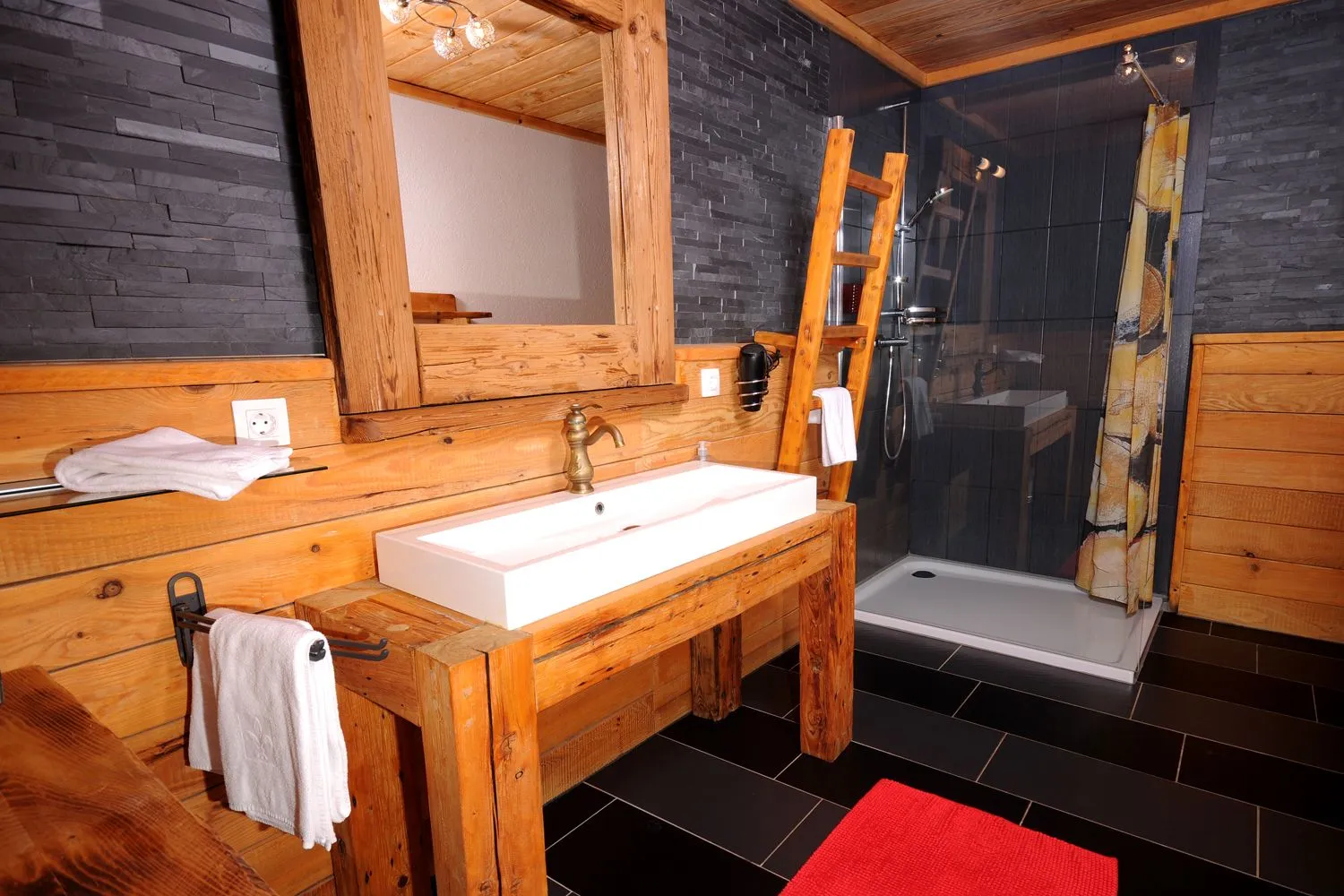 Zweites Badezimmer mit Holzwaschtisch und Glasdusche im Almchalet Dorfblick