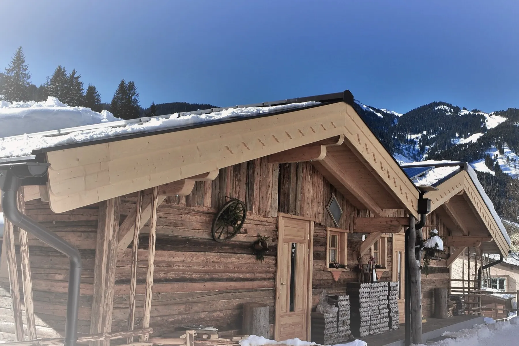 Holzchalets im Schnee in Mühlbach, dahinter verschneite Berge