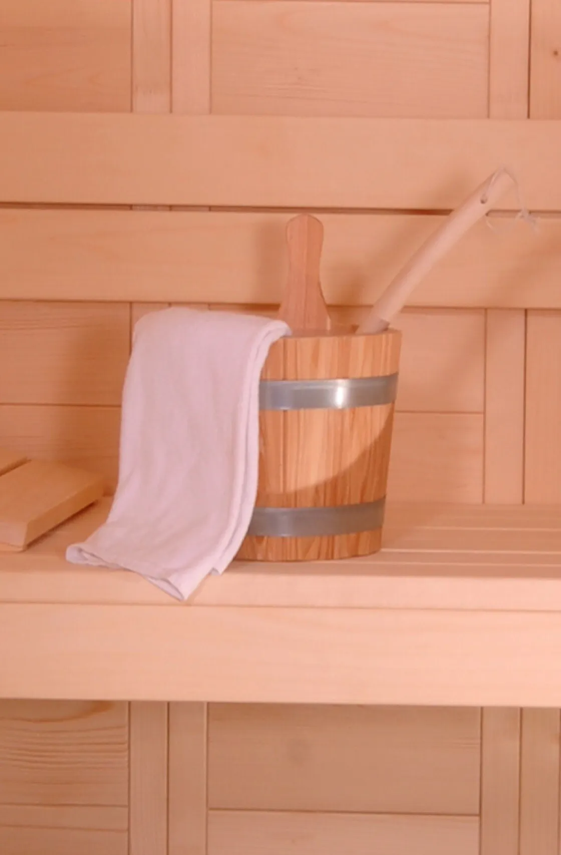 Saunakübel mit Kelle und Handtuch auf der Saunabank
