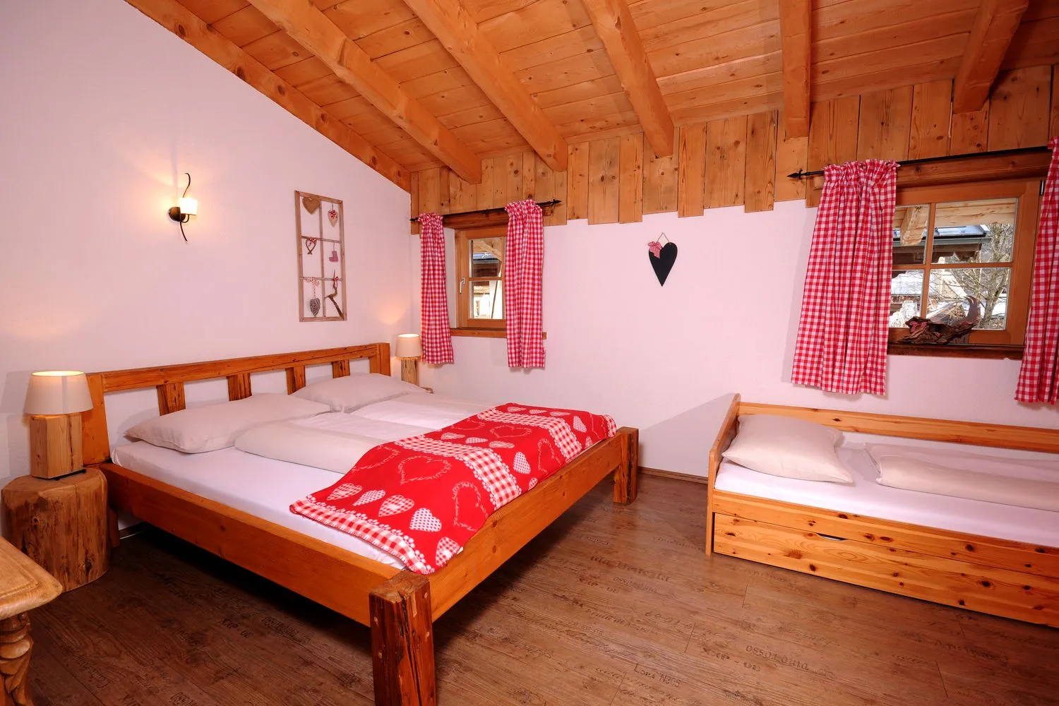Schlafzimmer mit Doppelbett und Einzelbett unter Holzbalken im Almchalet am Hochkönig