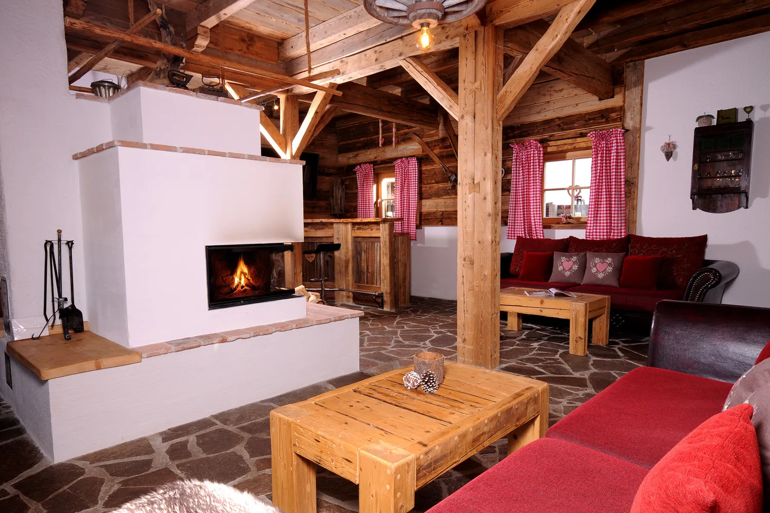Wohnstube mit Kachelofen und rotem Sofa im Almchalet am Hochkönig