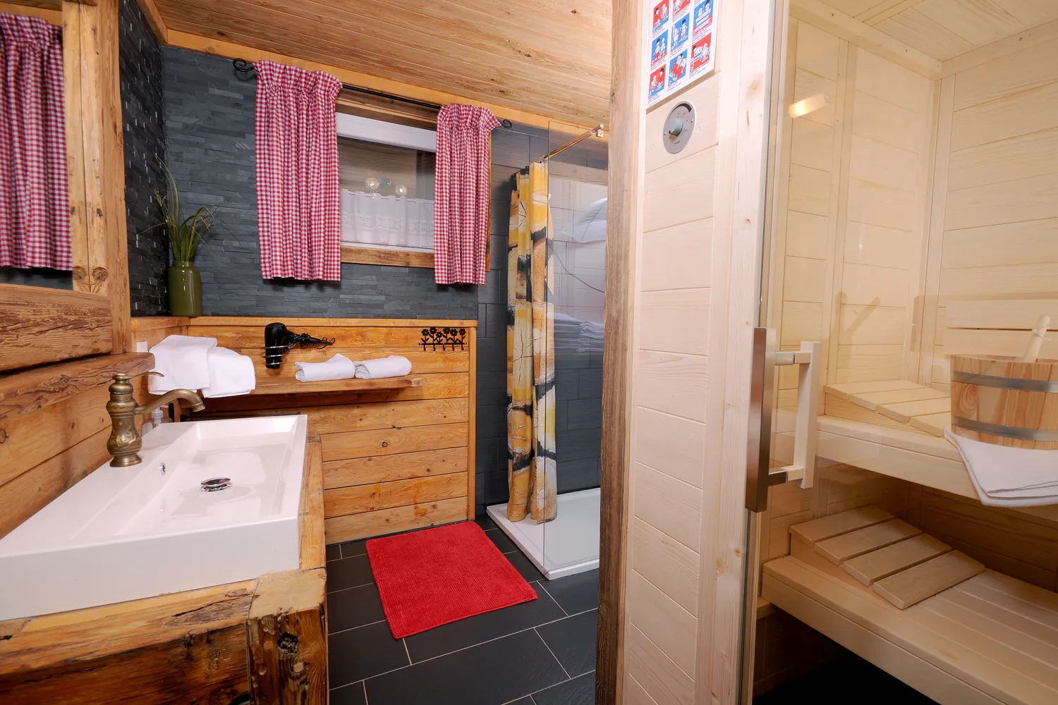 Badezimmer mit Waschtisch, dahinter die offene Saunatür im Almchalet Schneeberg