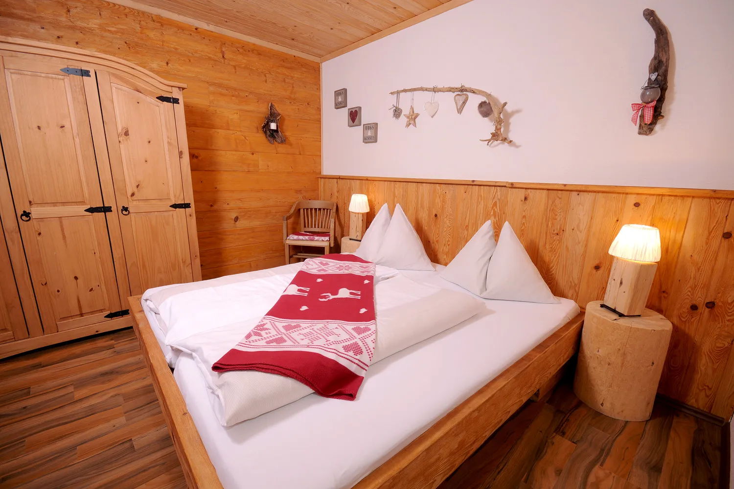 Schlafzimmer mit Doppelbett und Holzwand im Almchalet Schneeberg