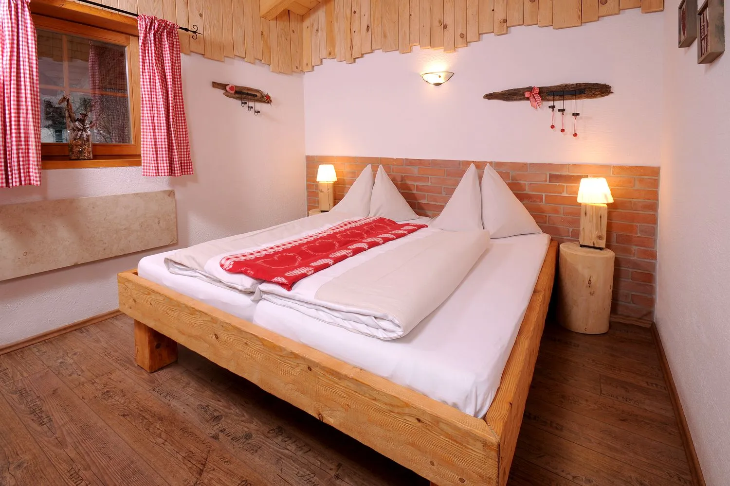 Schlafzimmer mit Holzdoppelbett und roter Tagesdecke im Almchalet Schneeberg
